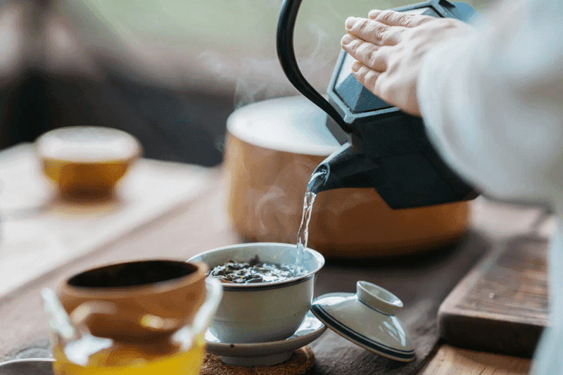 stock image pouring hot water from a kettle into a tea cup